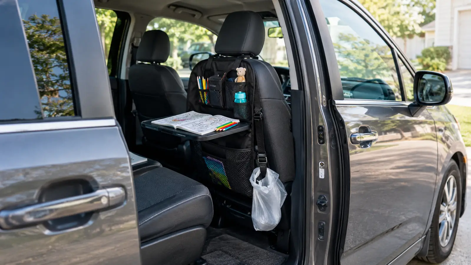 Open minivan door showing a backseat organizer hanging on the front seat with a coloring book on its fold-down tray
